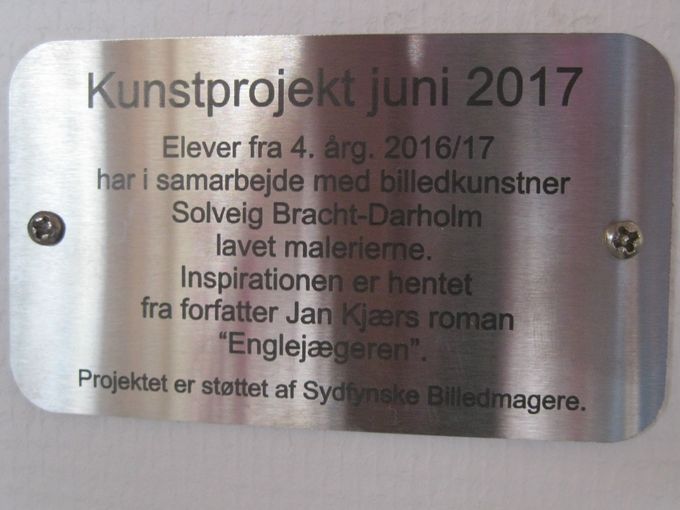 Efter et godt og spændende samarbejde blev projektet forsynet med en flot plakette, som beskriver projektets data.
Plaketten er forstørret meget op, så den er mulig at læse.
På væggen er den placeret nederst til højre for udsmykningen.
